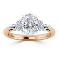 A rose gold ring with an oval diamond center, flanked by smaller round and marquise diamonds.