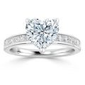 White gold ring with a large heart-shaped diamond and small diamonds set along the band.