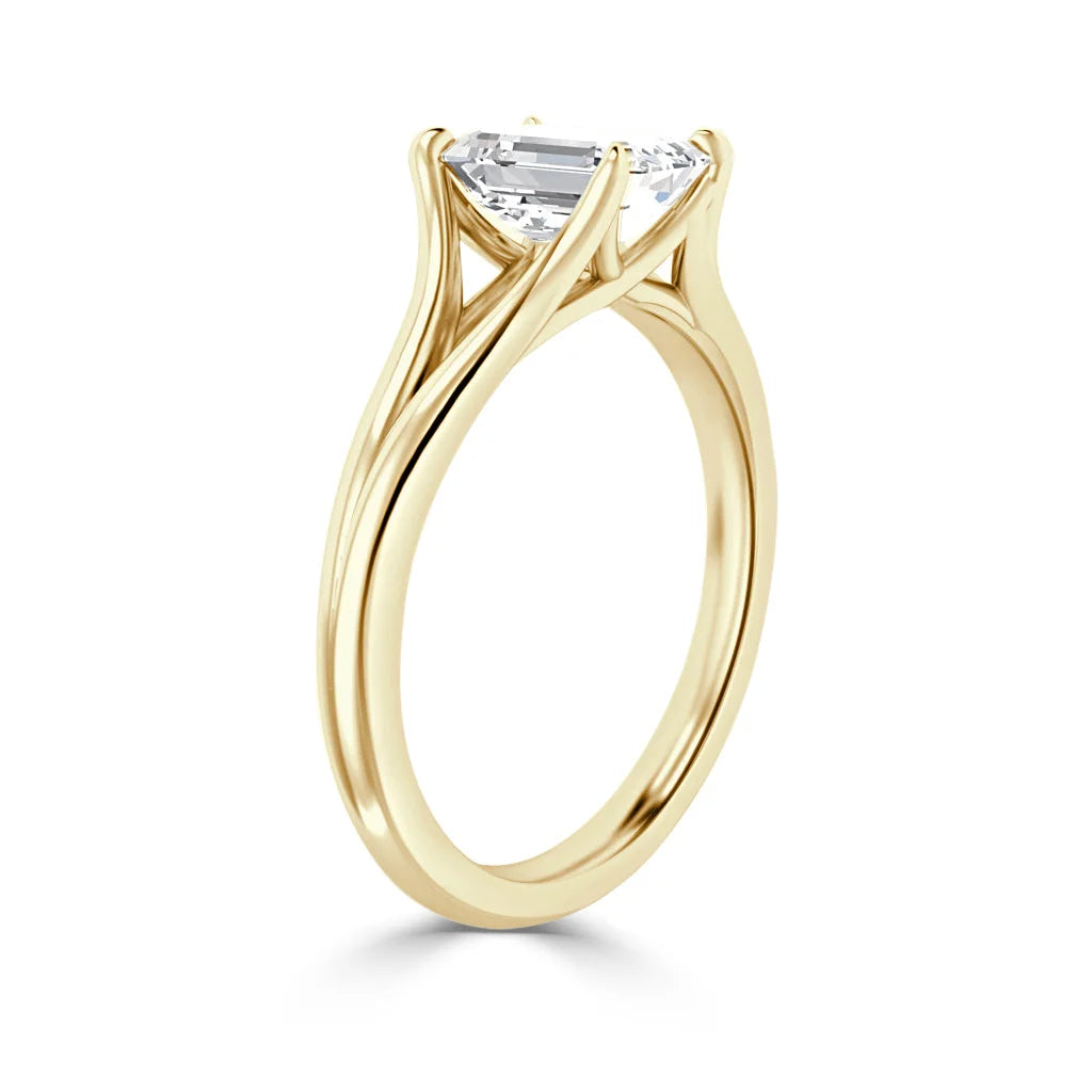 A gold engagement ring with a large emerald-cut diamond in a prong setting against a white background.