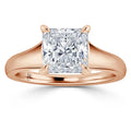 A rose gold ring with a large, square-cut diamond set in four prongs on a plain band.