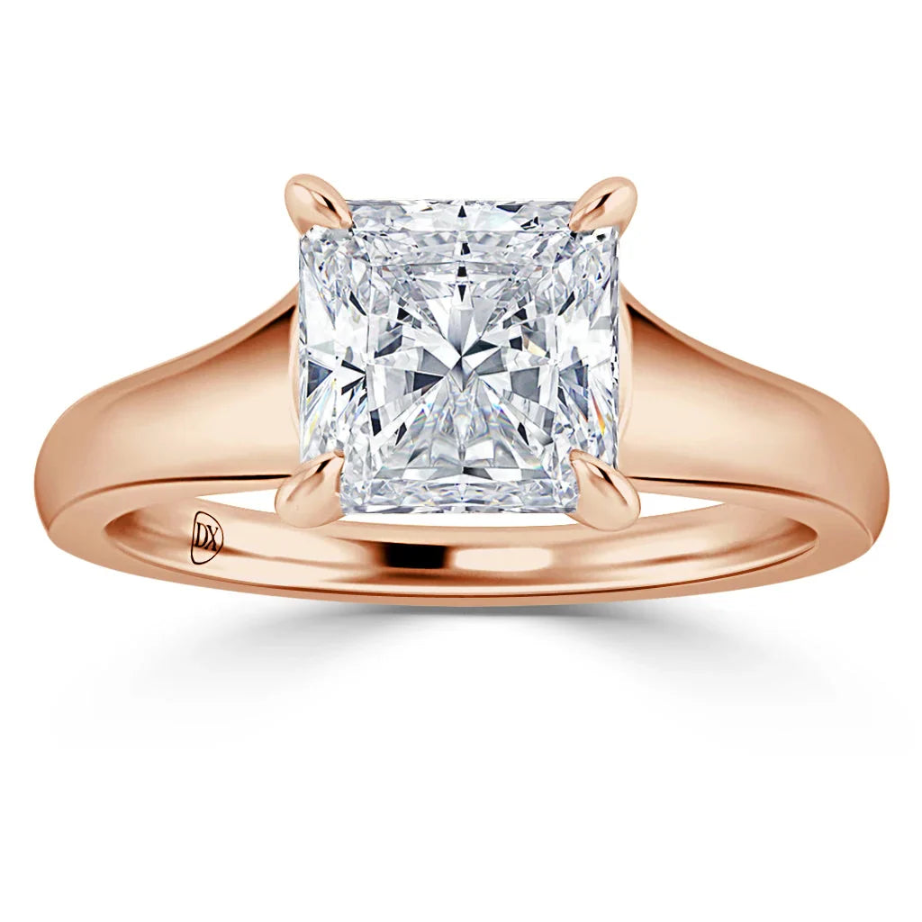 A rose gold ring with a large, square-cut diamond set in four prongs on a plain band.