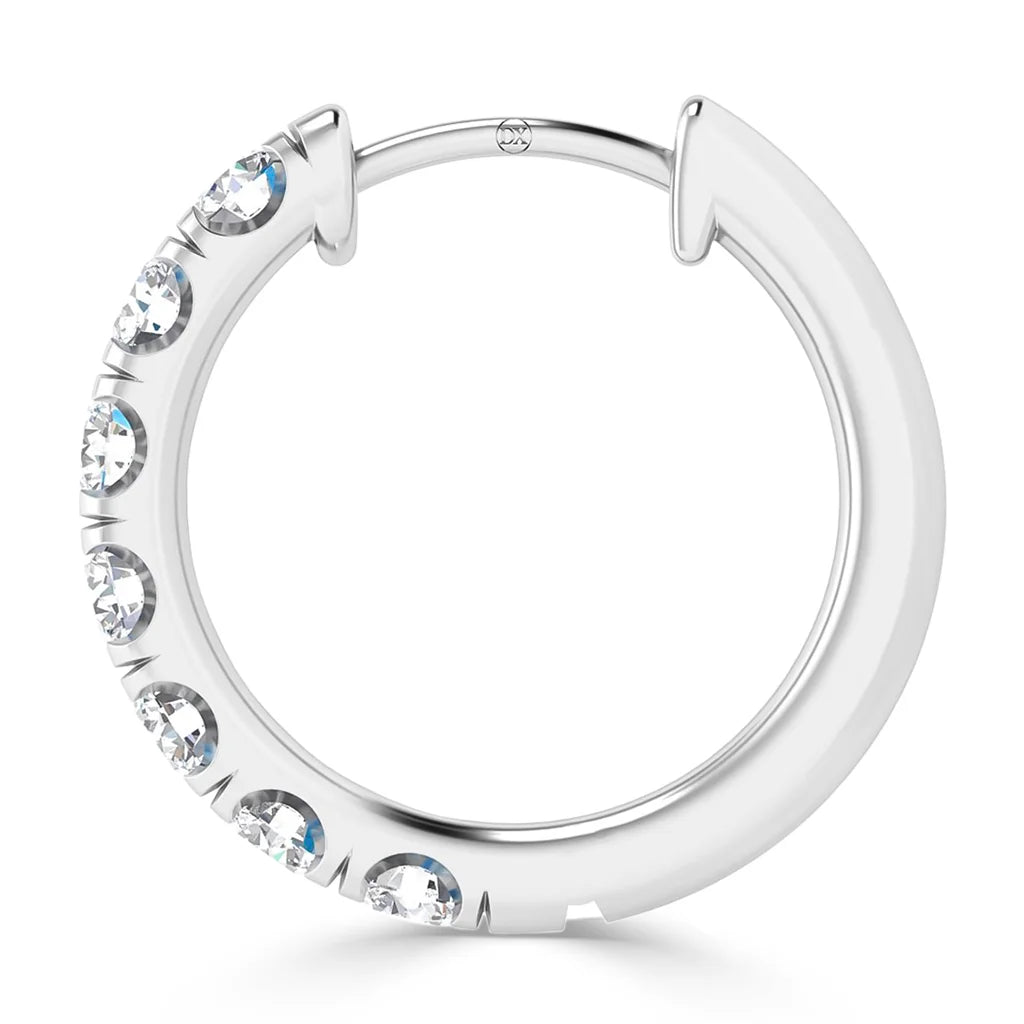 A silver hoop earring with seven evenly spaced round clear gemstones on one side.