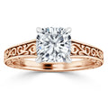 Rose gold ring with ornate filigree band and cushion-cut diamond in a four-prong white gold setting.
