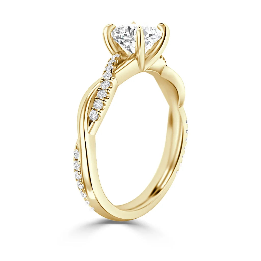 A gold ring with a round, prong-set diamond and pavé diamonds along a twisted band.