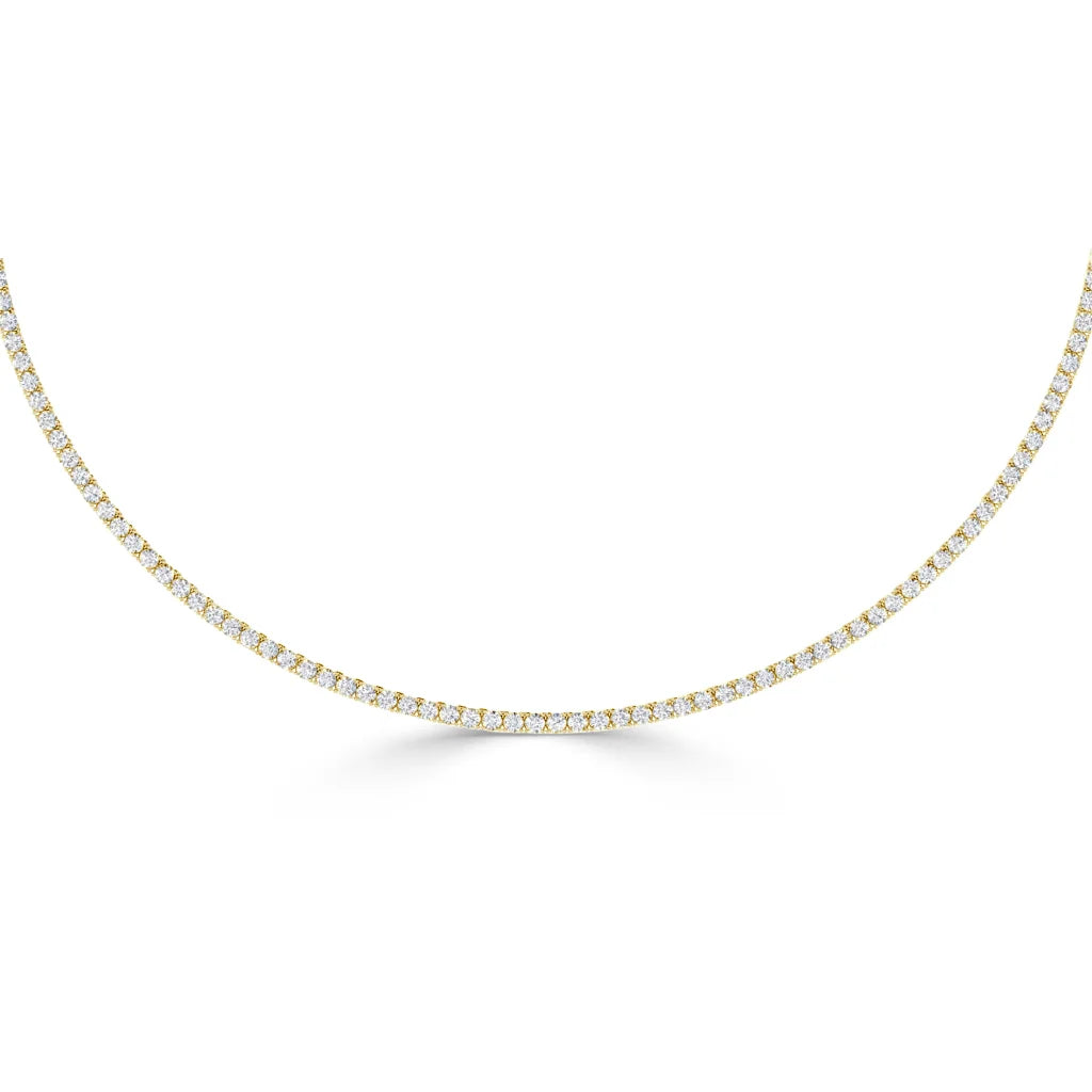 A delicate gold tennis necklace with evenly spaced round white diamonds in a continuous line.
