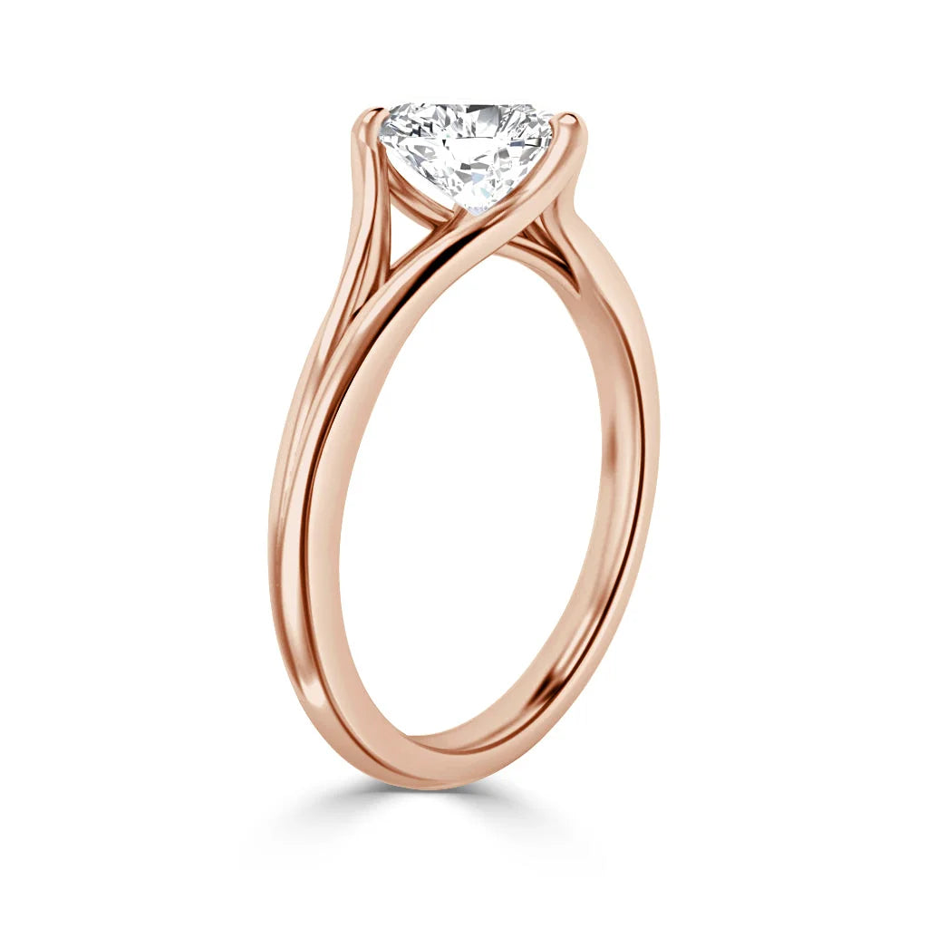 A rose gold ring with a round, prong-set diamond solitaire in a modern, twisted band design.