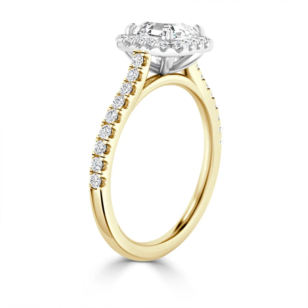 Gold ring with round diamond halo setting, side diamonds along the band, shown on a white background.