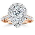 A pear-shaped diamond ring with a halo of diamonds on a rose gold band set with round diamonds.