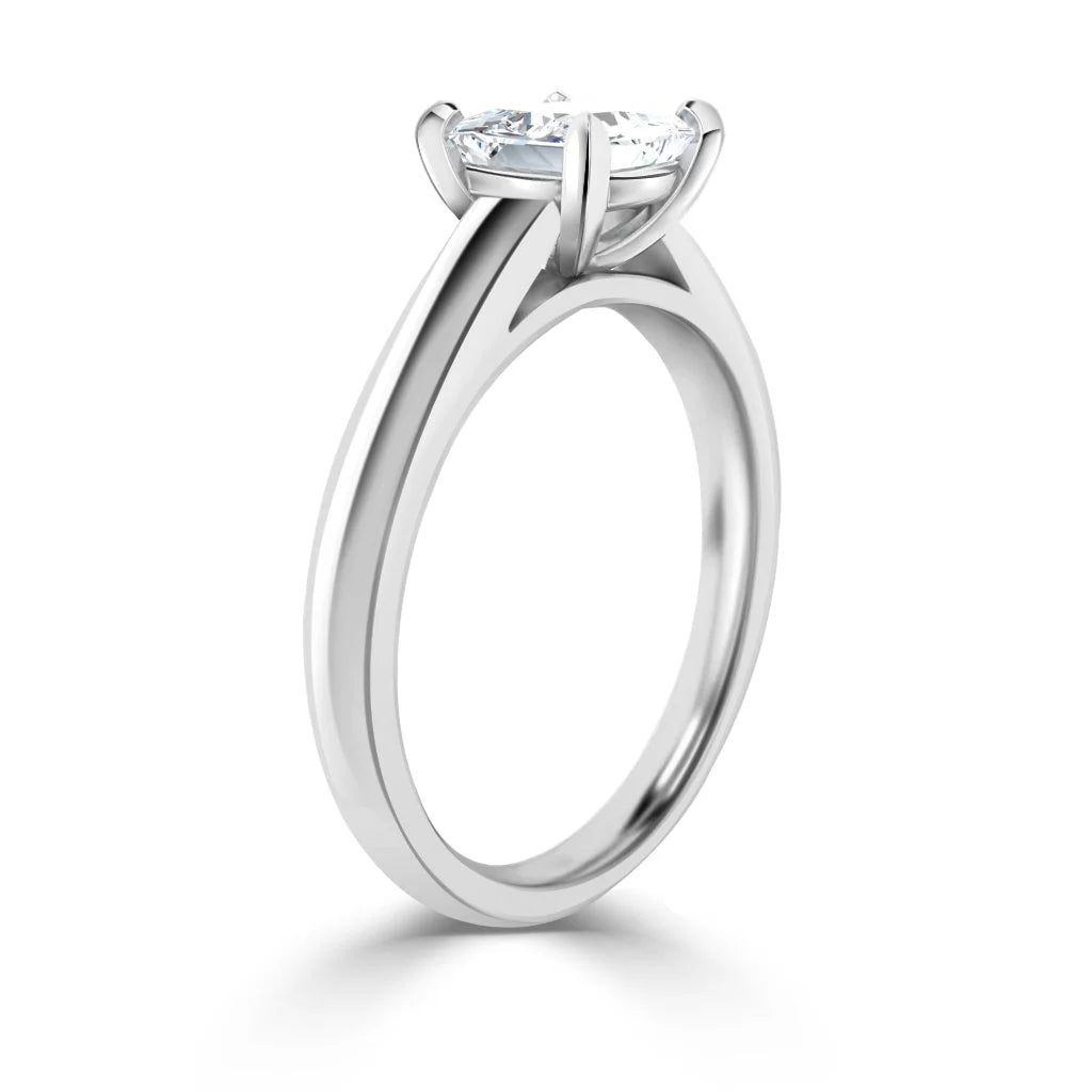 A silver engagement ring with a round solitaire diamond in a four-prong setting, viewed from the side.