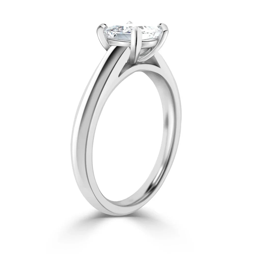 A silver engagement ring with a round solitaire diamond in a four-prong setting, viewed from the side.
