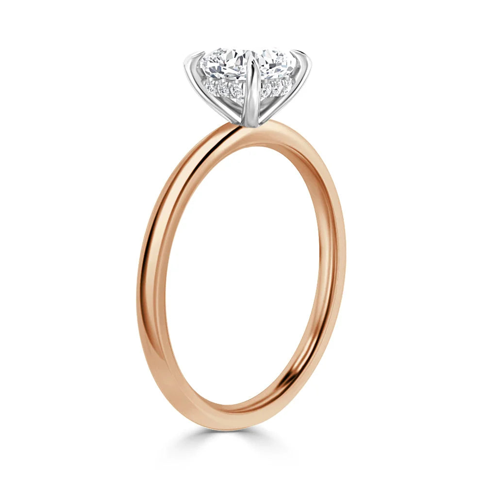 A rose gold engagement ring with a round, prong-set diamond solitaire on a plain band, on white background.