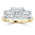 A gold band ring with three large, square-cut clear diamonds in a prong setting.