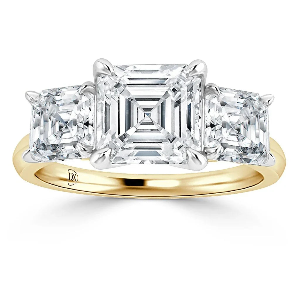 A gold band ring with three large, square-cut clear diamonds in a prong setting.