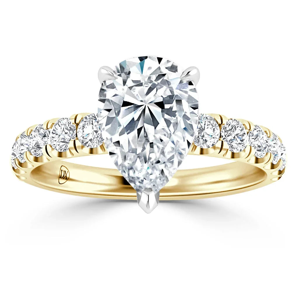 A gold ring with a large pear-shaped diamond center and round diamonds along the band, on a white background.