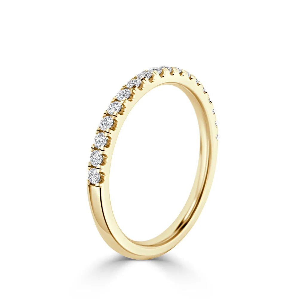 A thin gold ring with small round diamonds set along the top half, shown on a plain white background.
