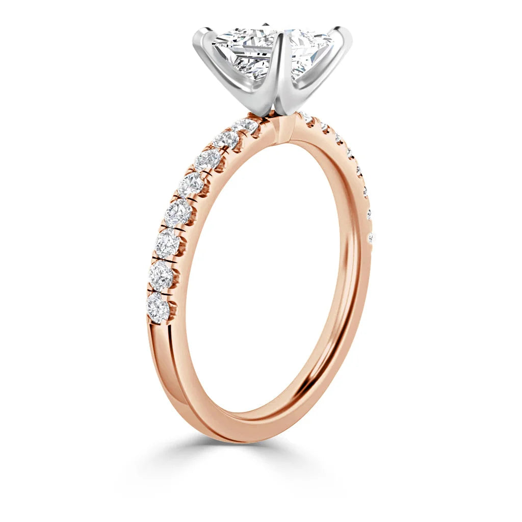 A rose gold ring with a round diamond solitaire and small diamonds along the band, shown at an angle.