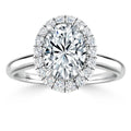 A white gold ring with an oval-cut center diamond, surrounded by a halo of smaller diamonds.