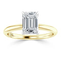 Emerald-cut diamond solitaire ring with a yellow gold band, viewed from the front against a white background.