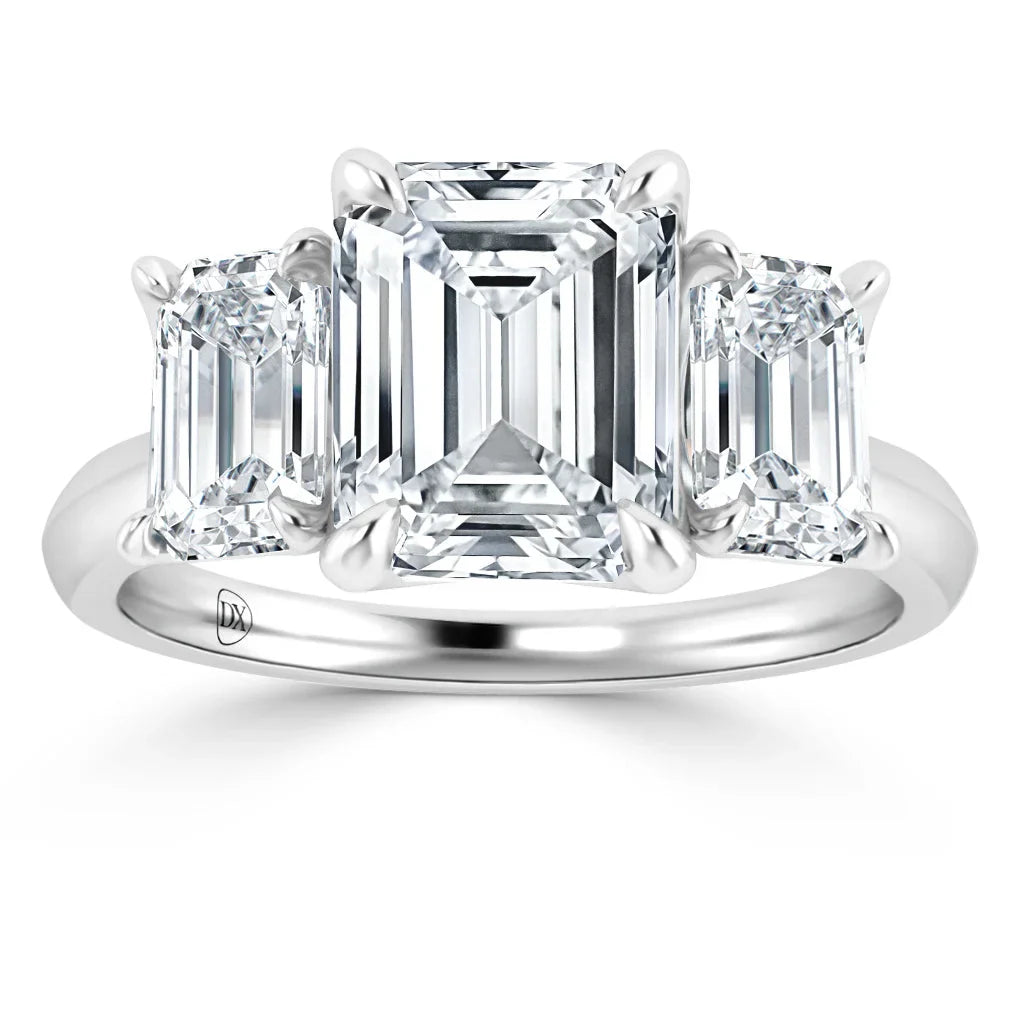 A platinum ring with three emerald-cut diamonds, the center stone flanked by two smaller side diamonds.