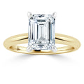 Gold band ring with a large emerald-cut diamond set in four prongs, shown on a white background.