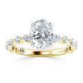 Gold ring with an oval-cut diamond center and round side diamonds set in a twisted band design.