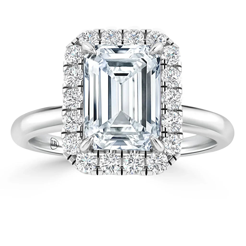 Emerald-cut diamond ring with a halo of round diamonds on a sleek white gold band, shown on white background.