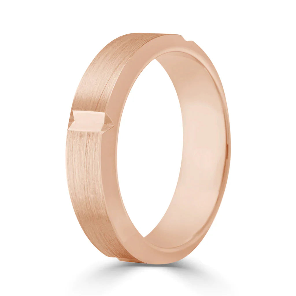 A rose gold ring with a brushed finish and a small engraved arrow detail on the outer band.