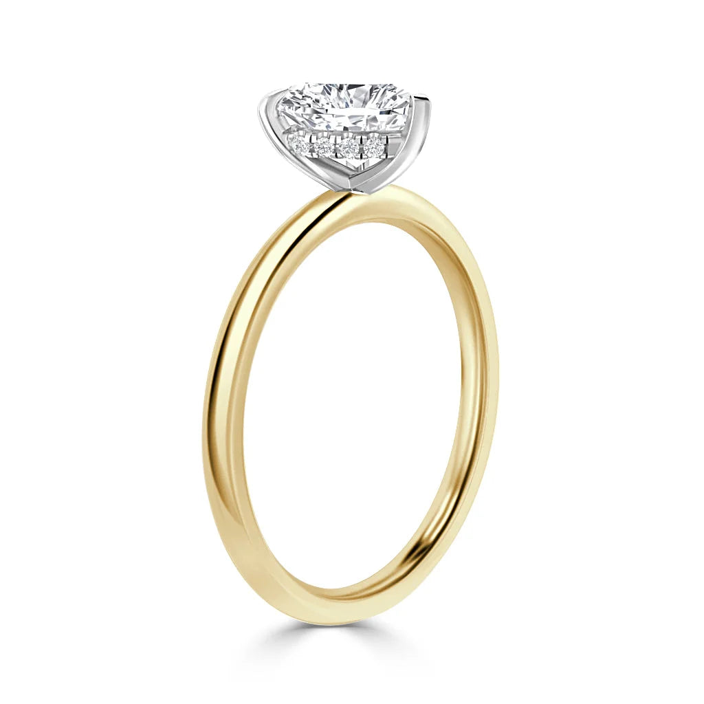 A gold solitaire ring with a round-cut diamond in a white prong setting, viewed from the side on a white background.