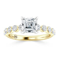 A gold ring with an Asscher-cut diamond center and round diamonds along the band, engraved with DX inside.