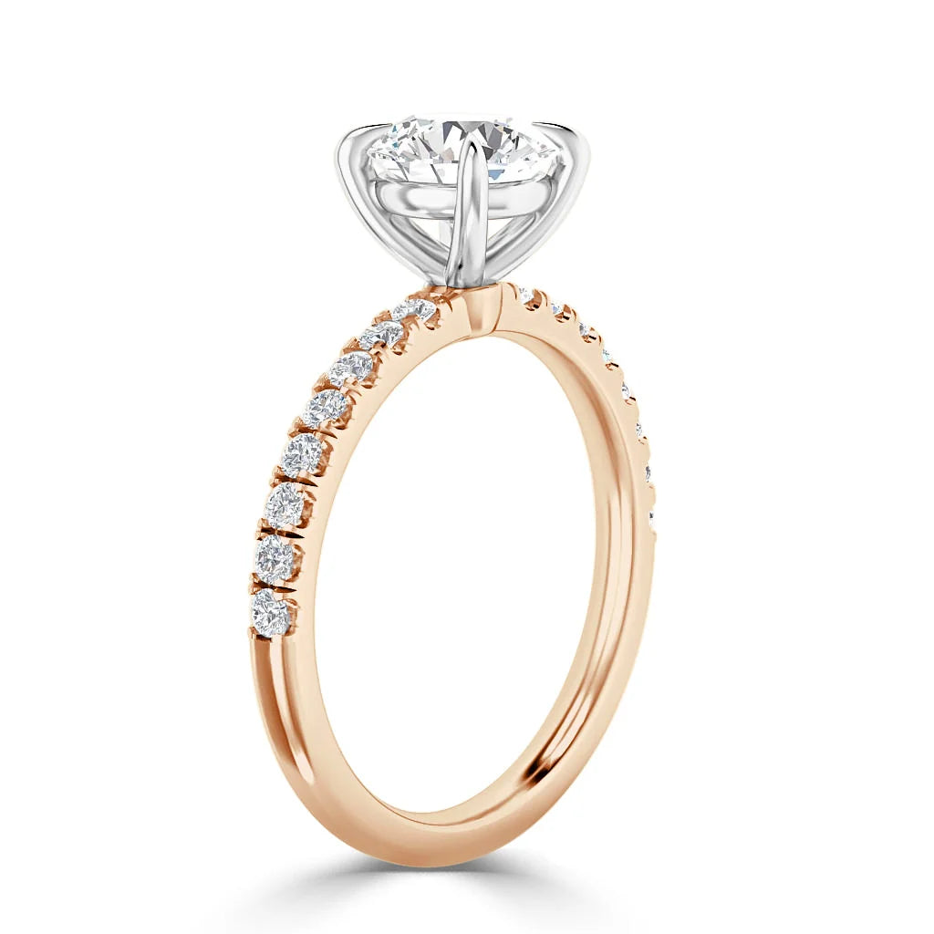 Rose gold ring with pavé diamonds on the band and a large round diamond in a white gold prong setting.