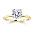 A round solitaire diamond ring with a yellow gold band and white gold prong setting, shown on a white background.
