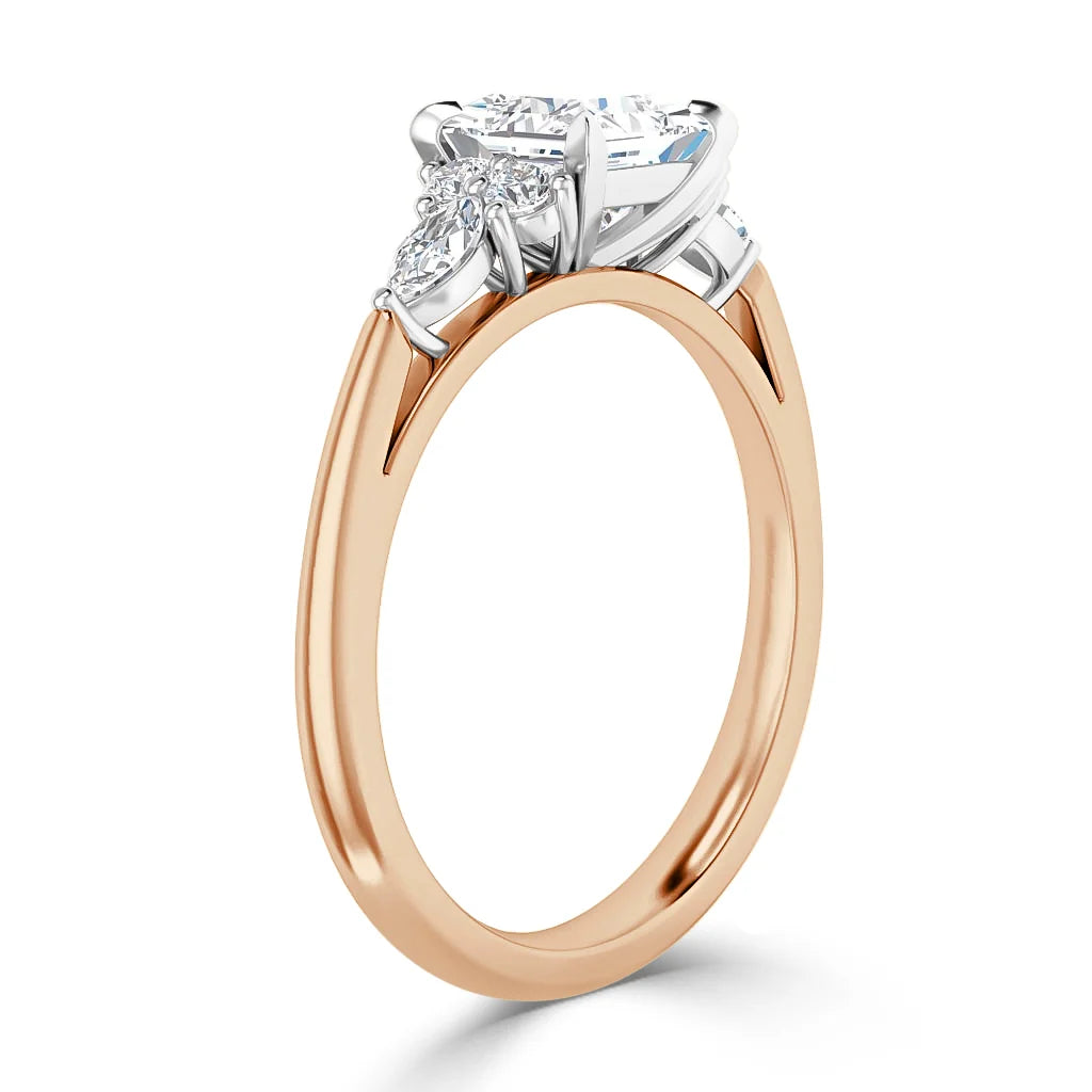 Rose gold ring with a round center diamond and two marquise side diamonds set in a white gold prong setting.