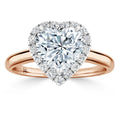 Heart-shaped diamond ring with a halo of smaller diamonds on a rose gold band, shown on a white background.