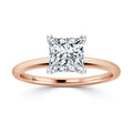 A rose gold ring with a large princess-cut diamond solitaire set in a simple, elegant band.