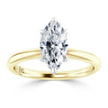 A gold band ring with a marquise-cut diamond solitaire set in six prongs, displayed on a white background.