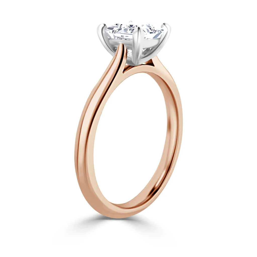 A rose gold ring with a round white diamond solitaire held by a four-prong white gold setting.