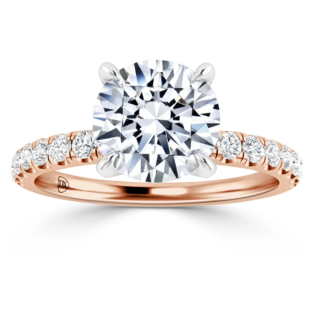 Rose gold ring with round solitaire diamond and small diamonds along the band, shown on a white background.