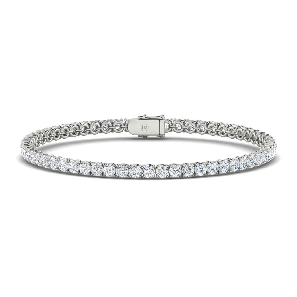 A silver tennis bracelet with a row of round-cut white diamonds and a secure clasp, displayed on a white background.
