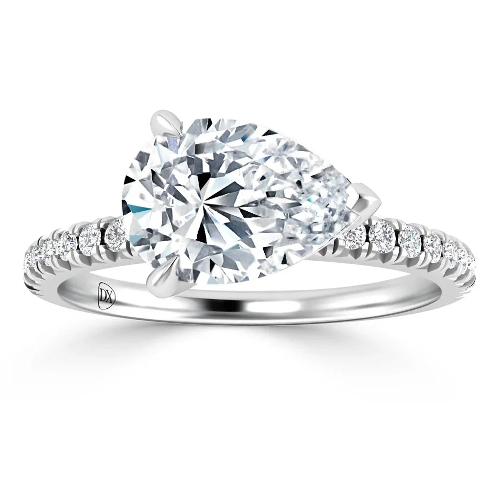A pear-shaped diamond ring with a pavé band featuring small round diamonds on a white metal band.