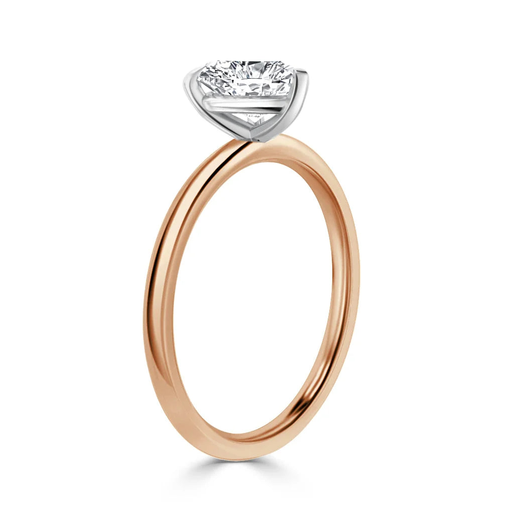 A rose gold ring with a round, solitaire diamond set in a white gold bezel on a plain band.
