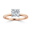 A rose gold ring with a single cushion-cut diamond in a four-prong white gold setting, shown on a white background.