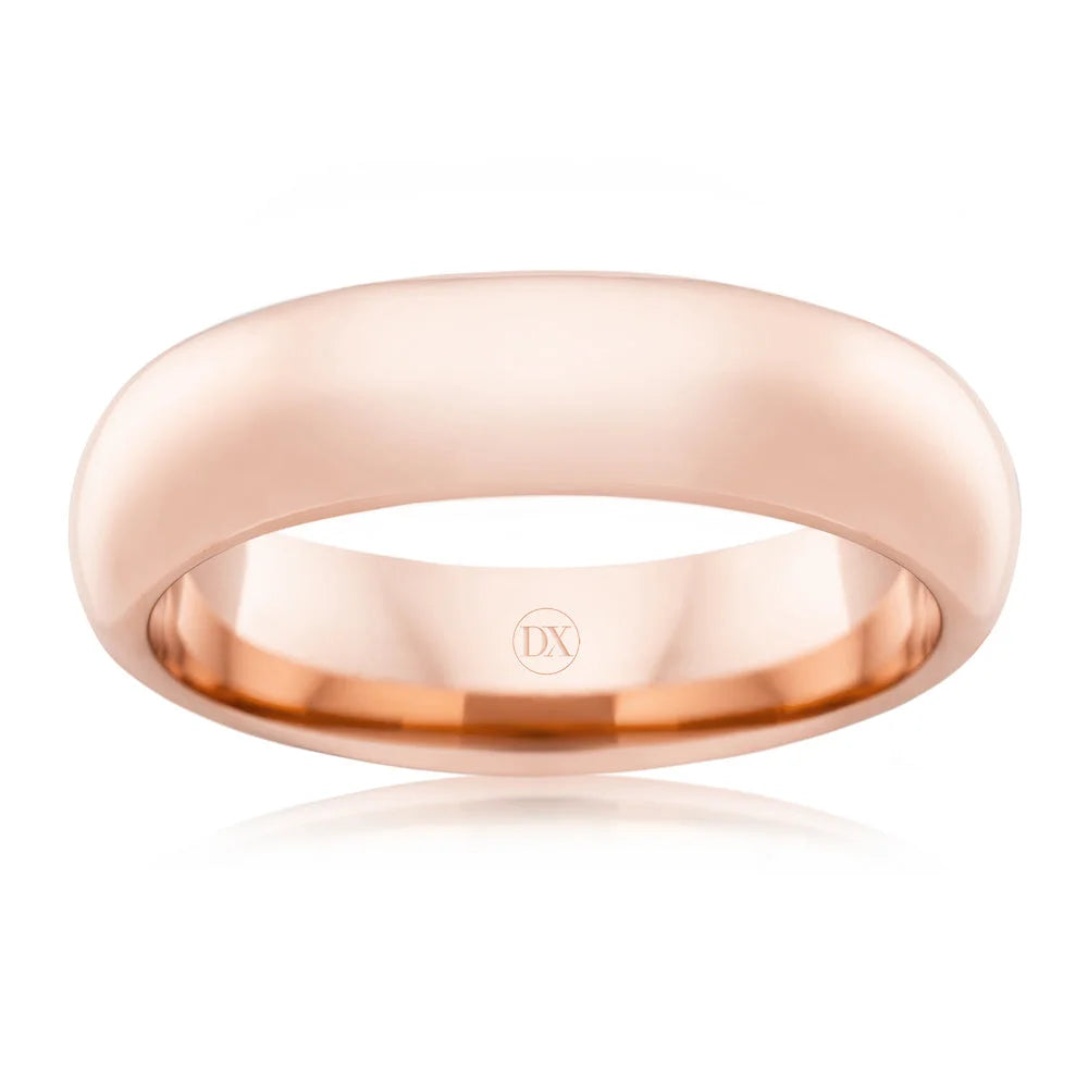 A polished rose gold wedding band ring with a smooth, rounded surface and DX engraved inside.
