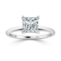 A princess-cut diamond solitaire ring with a thin, polished white gold band on a white background.