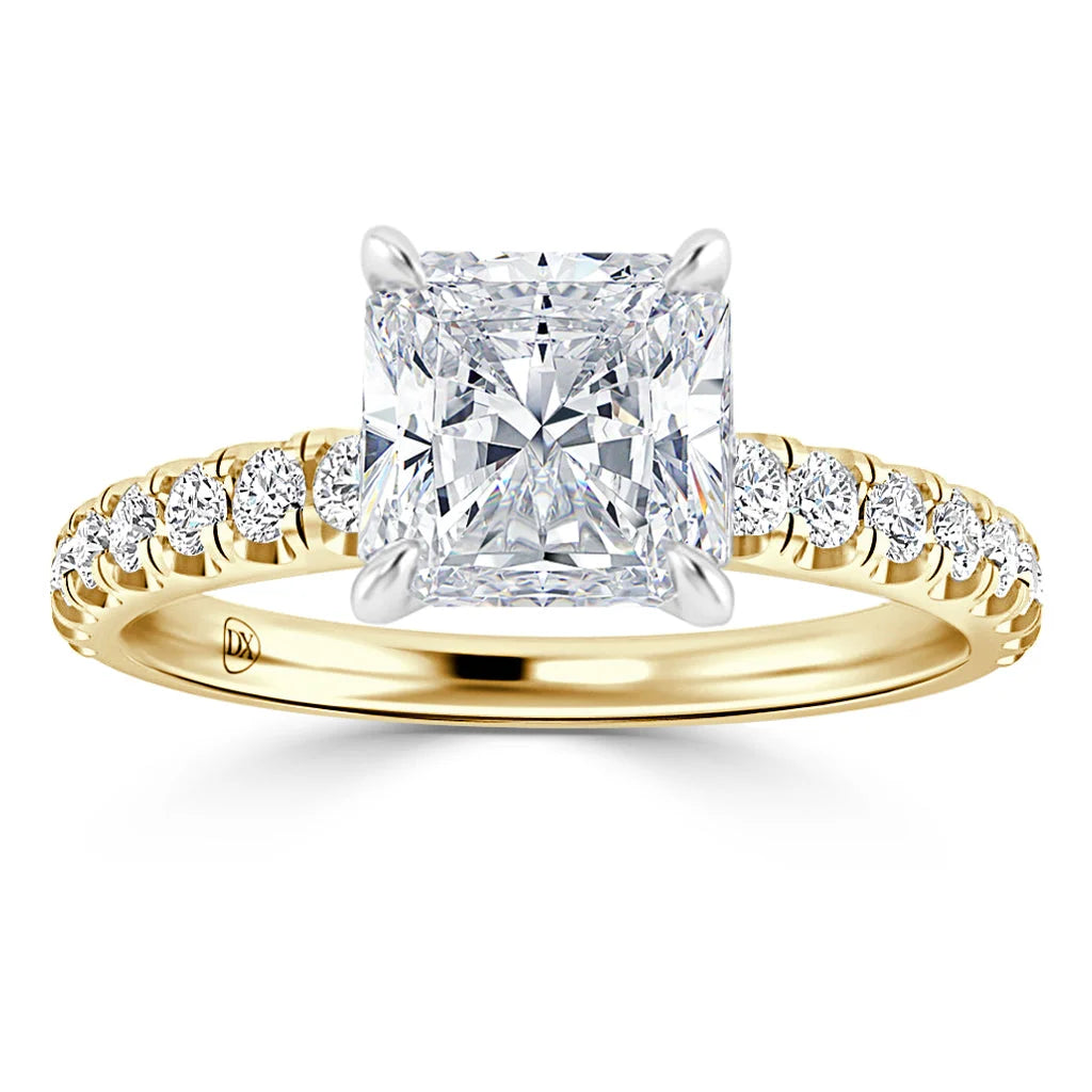 A gold ring with a large princess-cut diamond center and small diamonds set along the band.