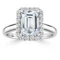 Emerald-cut diamond ring with a halo of round diamonds on a split shank white gold band, shown from the front.