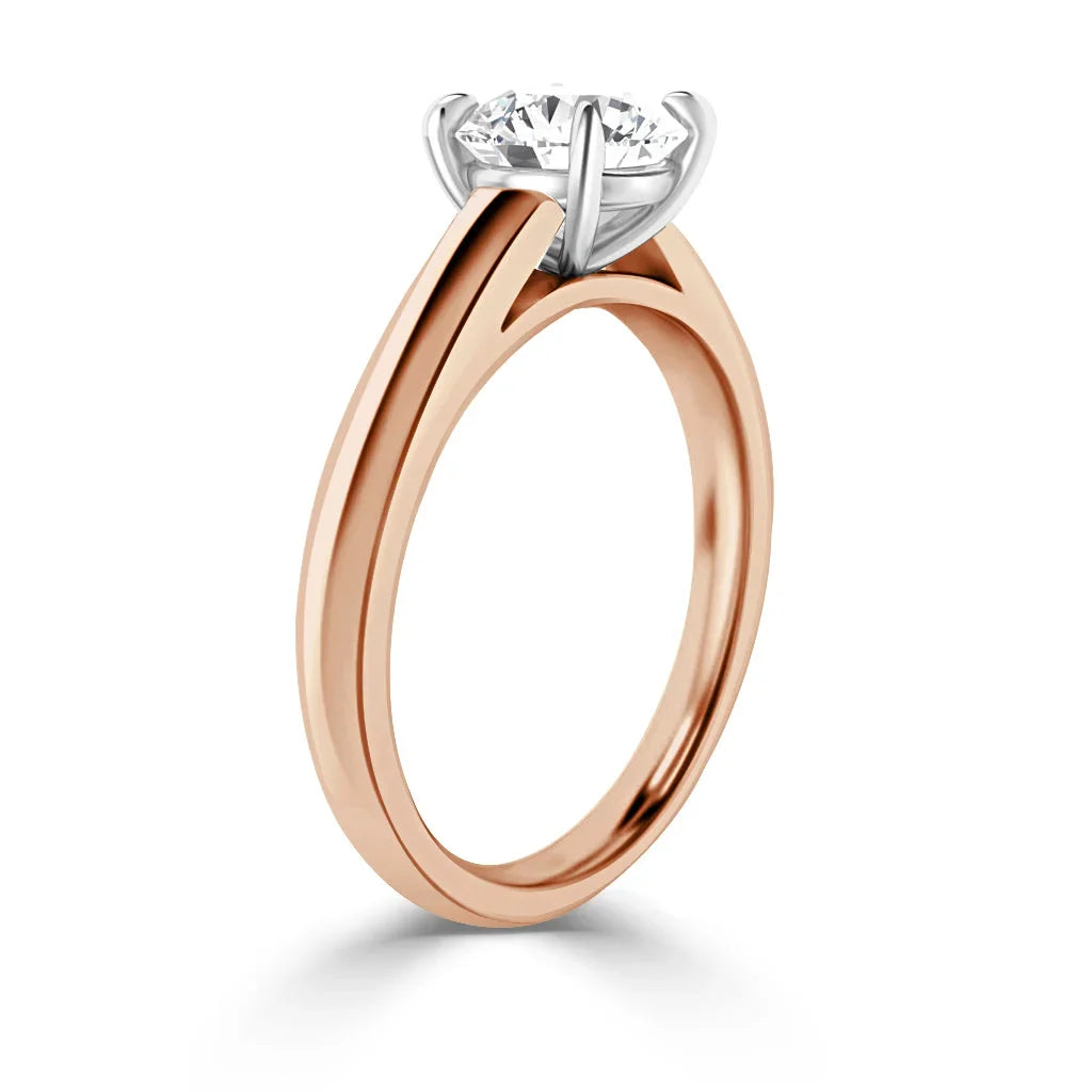 Rose gold engagement ring with a round solitaire diamond in a white gold prong setting, shown from the side.