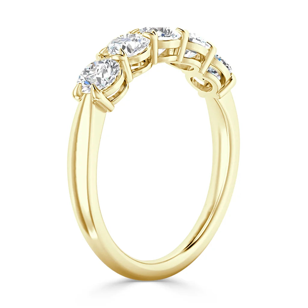 A gold ring with three round diamonds in prong settings, shown angled to highlight the side profile.