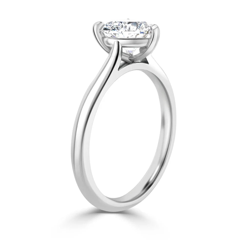 A solitaire diamond ring with a thin, polished white gold band and a four-prong setting, shown from the side.
