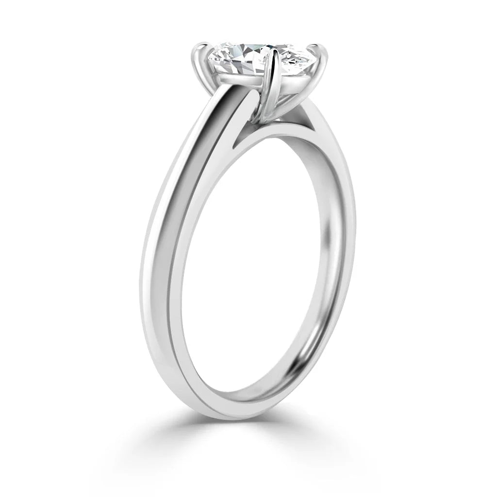 A silver solitaire engagement ring with a round brilliant diamond held by four prongs, viewed from the side.