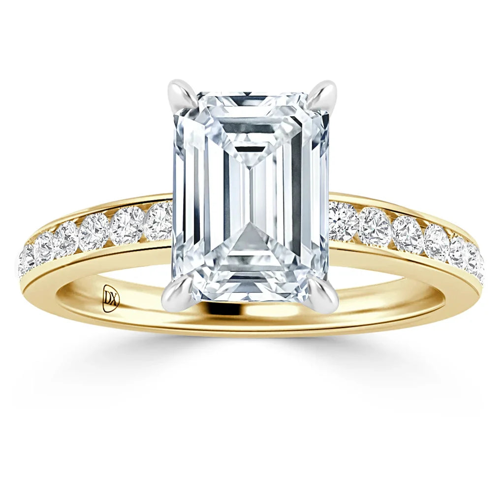 Emerald-cut diamond ring with gold band and round side diamonds set along the upper half of the band.